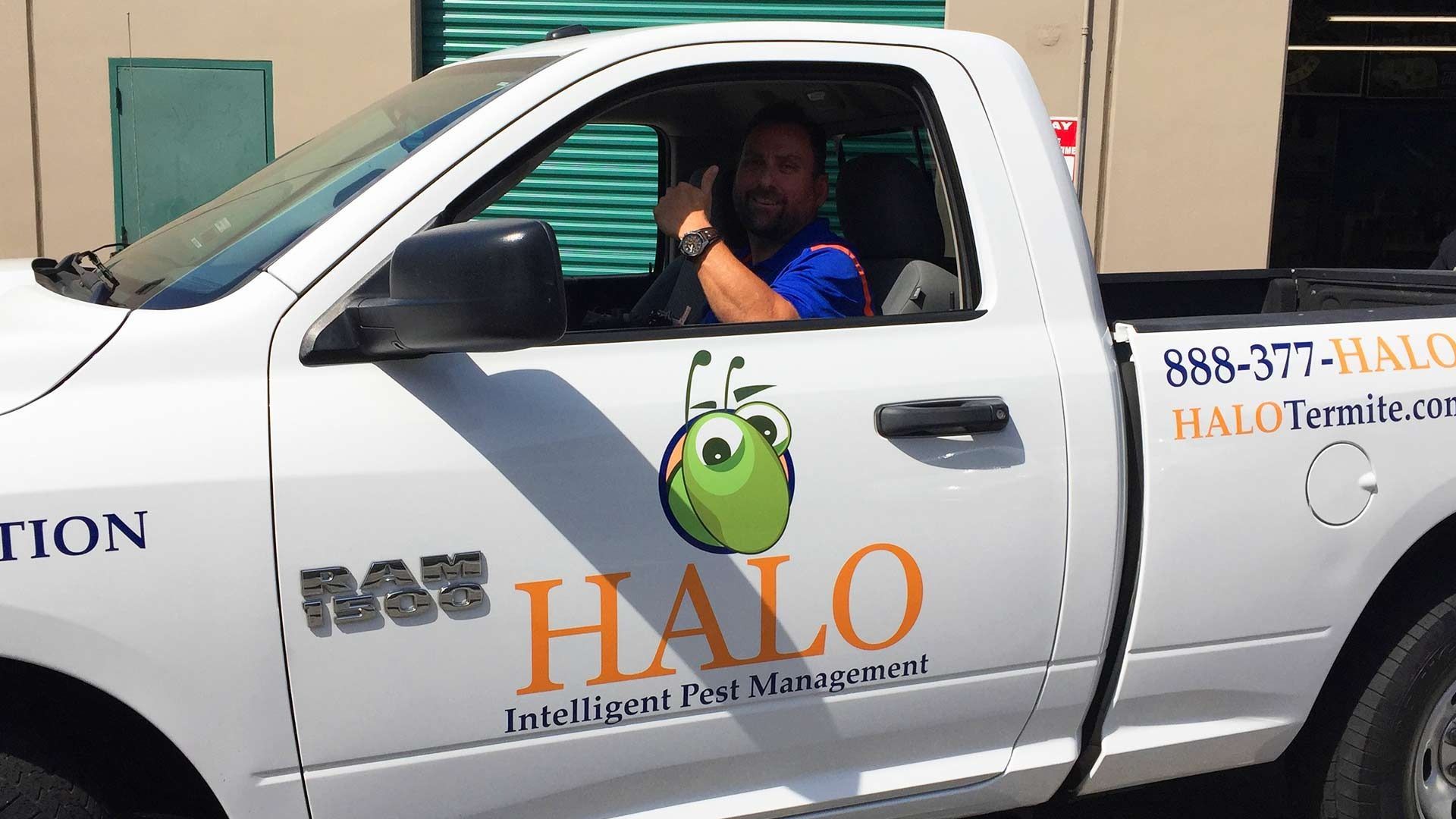 A smiling person in a blue shirt gives a thumbs up from the driver's seat of a white Halo Pest Management service truck.