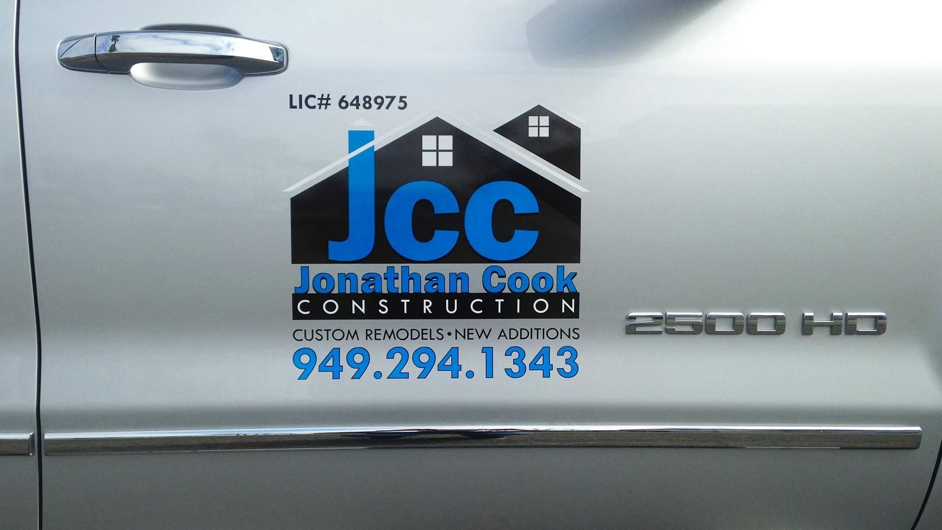 The side of a silver truck with a logo for Jonathan Cook Construction, including the phone number 949.294.1343.