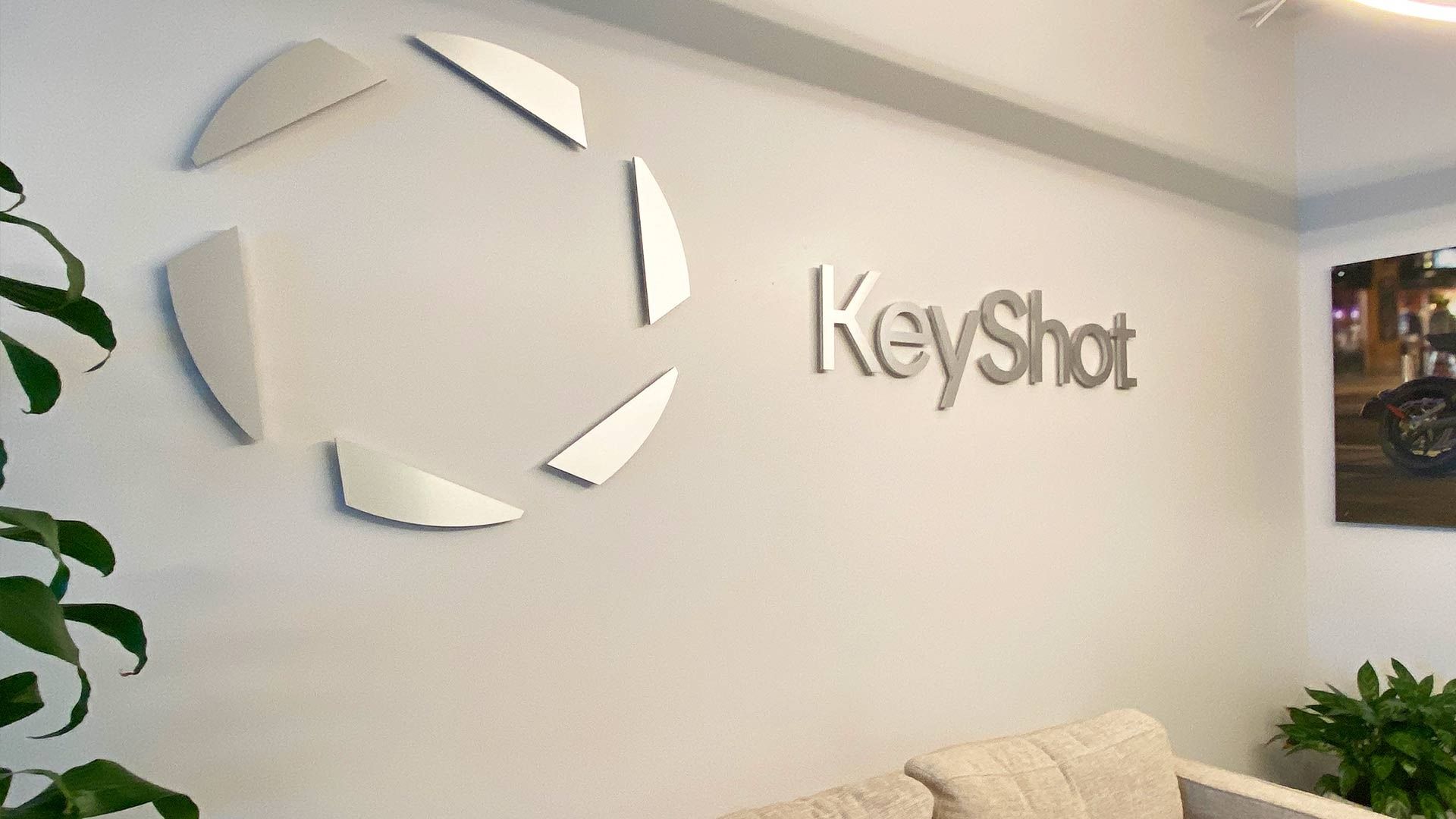 The KeyShot company logo and wordmark mounted on a light-colored office wall, with greenery visible on the sides.