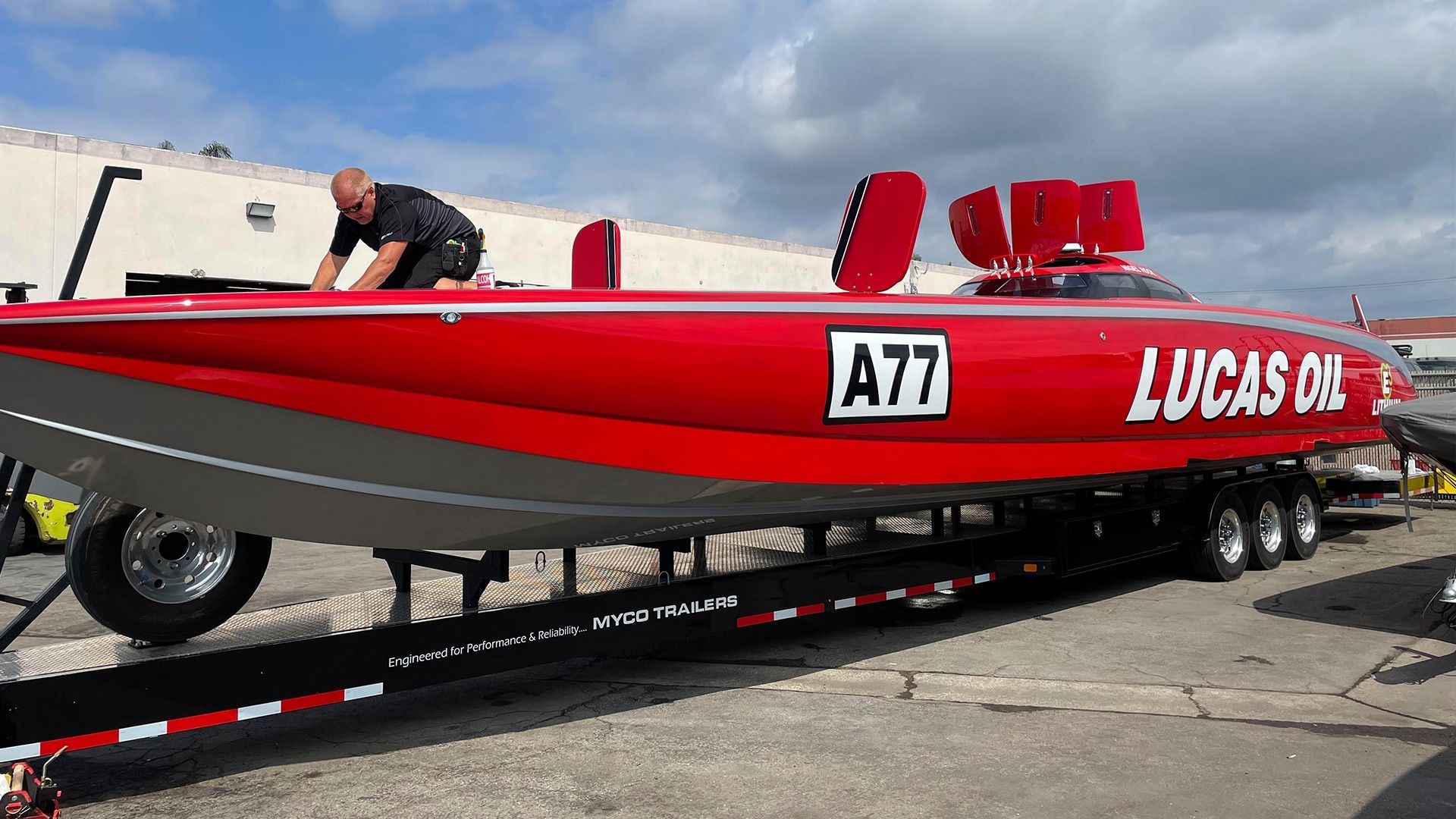 A person stands on a red Lucas Oil racing boat with 