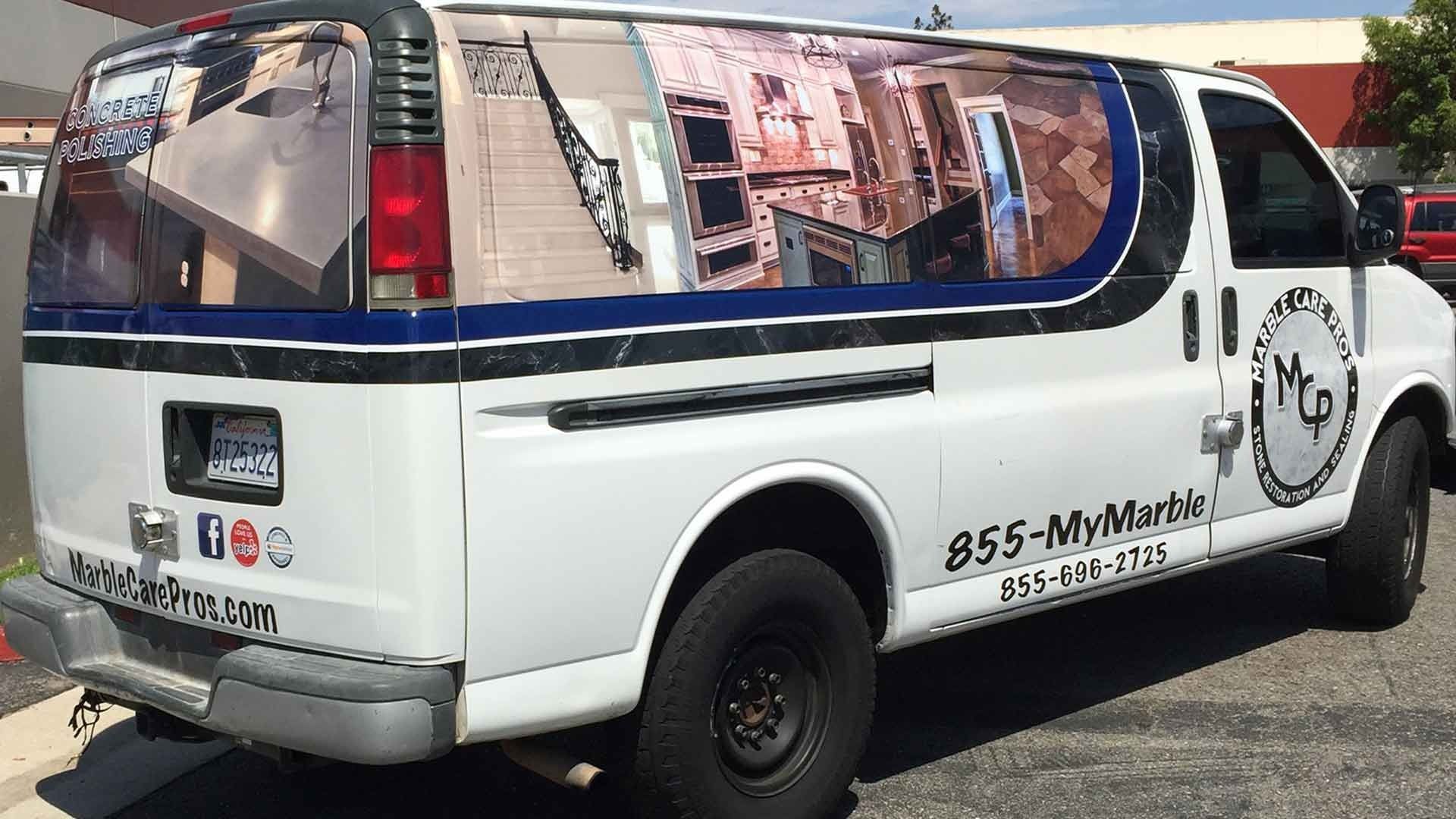 A white commercial work van with custom branding, including photos of stone interiors and the phone number 855-MyMarble.