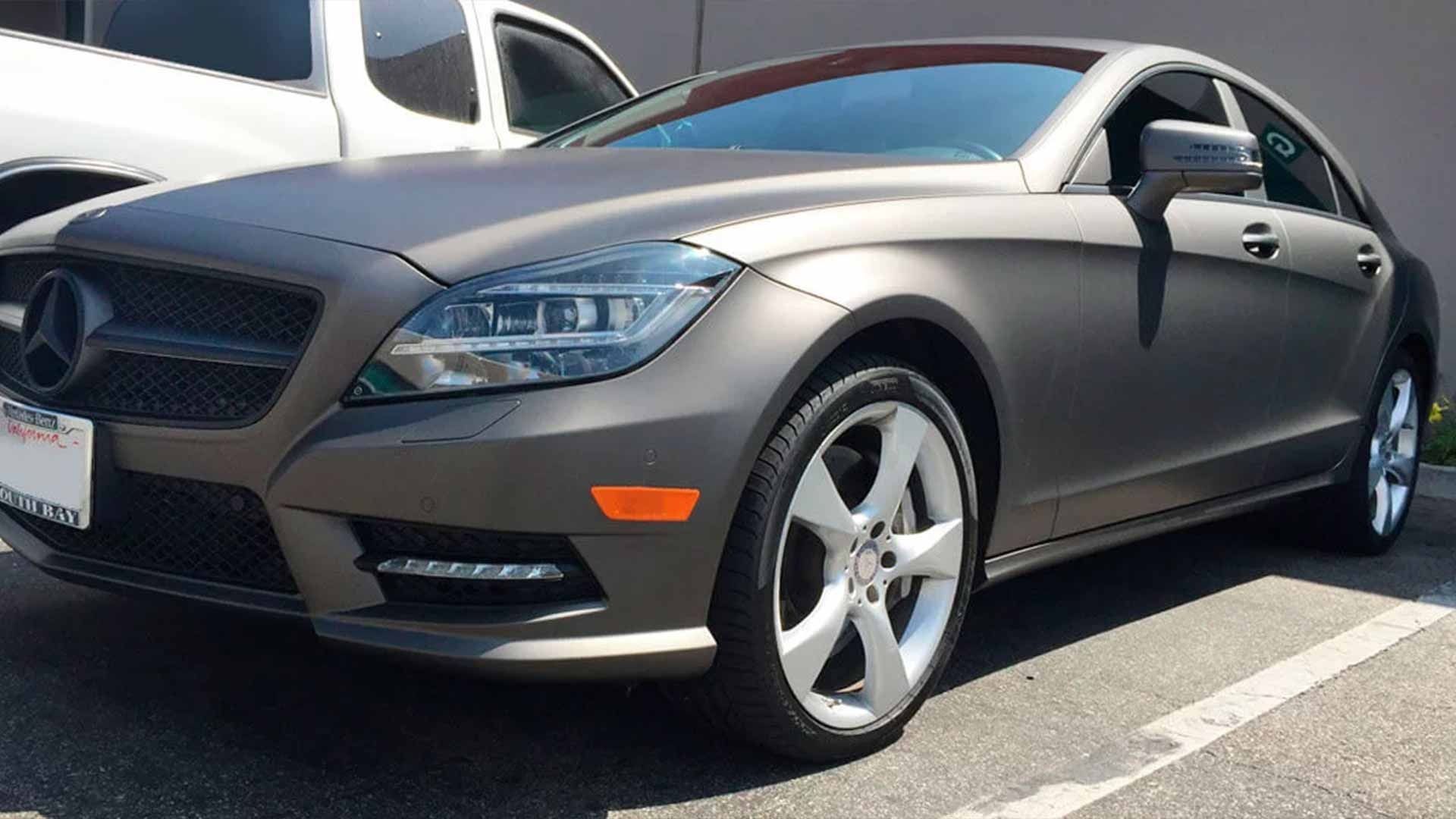 A matte charcoal Mercedes-Benz sedan parked outdoors on an asphalt surface.