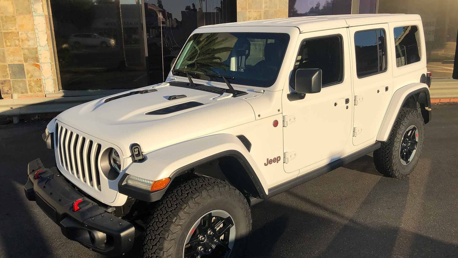 A white Jeep Wrangler Unlimited parked on pavement during the day.