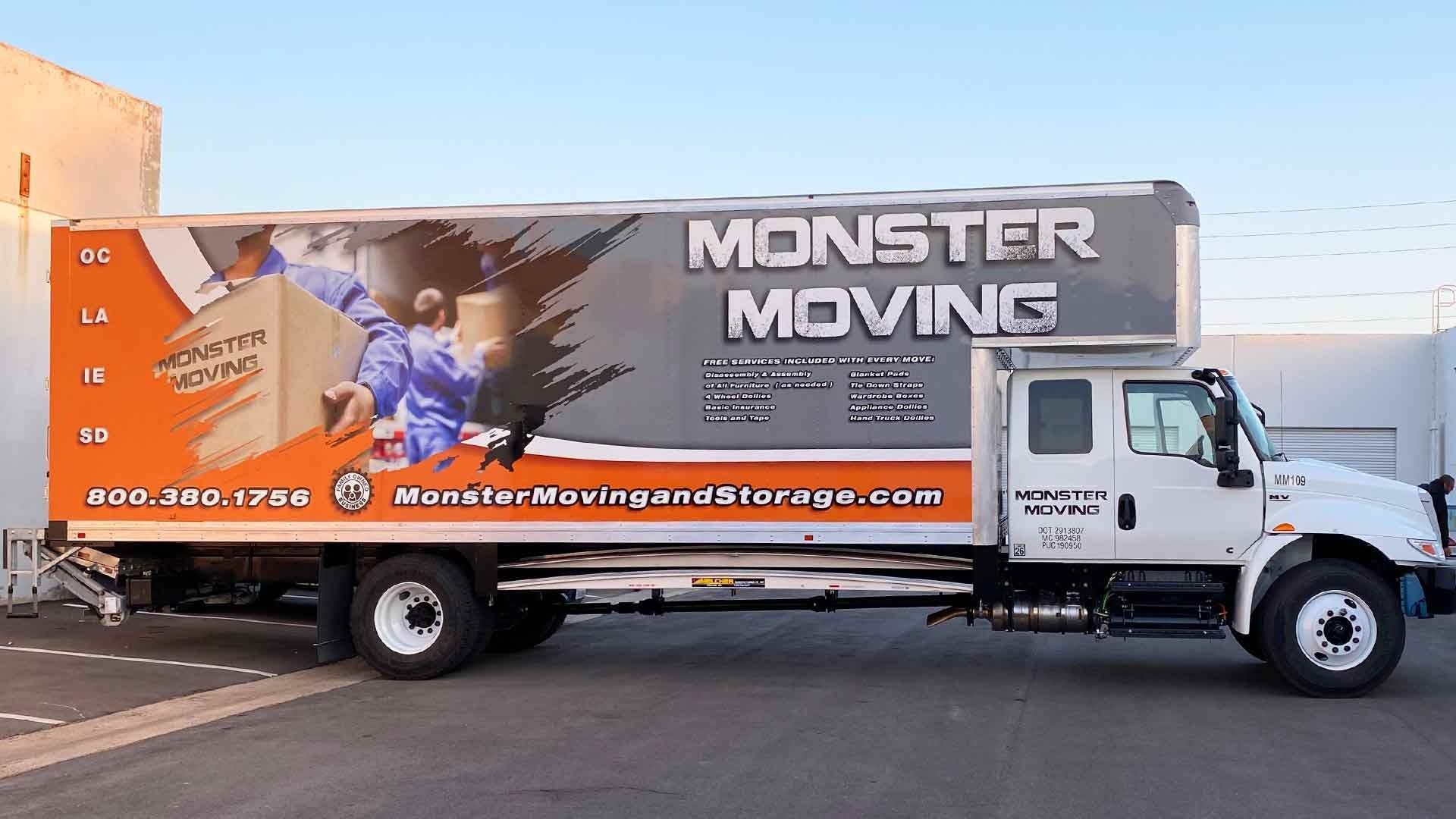 A white Monster Moving box truck parked on asphalt with orange and gray branding, featuring the company's website and phone.