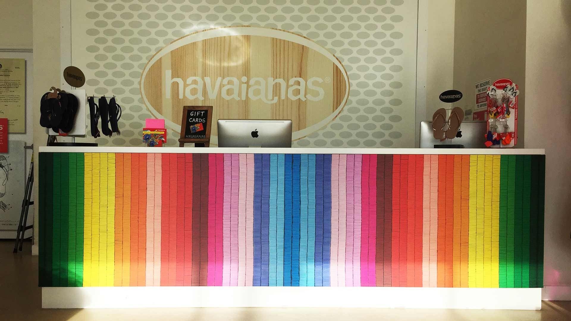 A checkout counter in a Havaianas store featuring a vibrant, multi-colored vertical striped front panel.