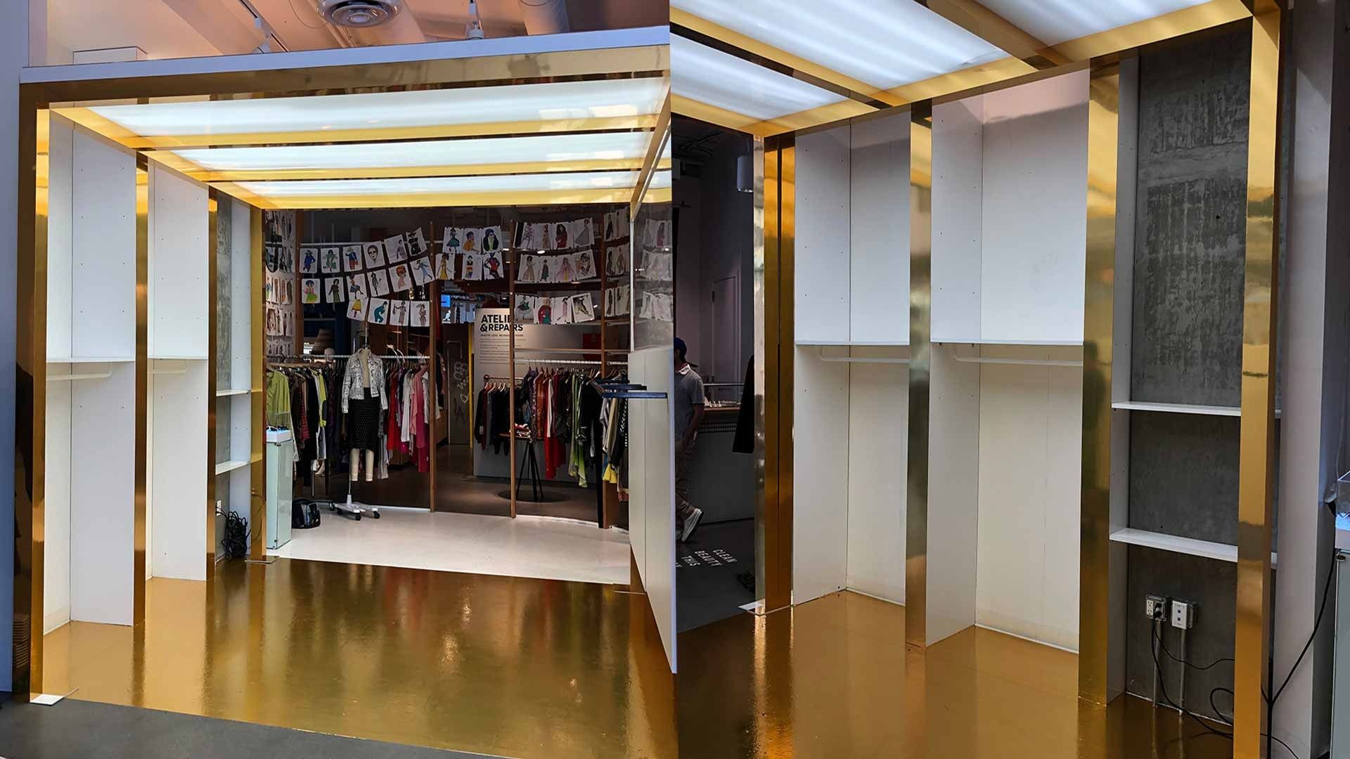 A modern retail store entrance featuring white shelving units accented with gold trim and reflective gold flooring.
