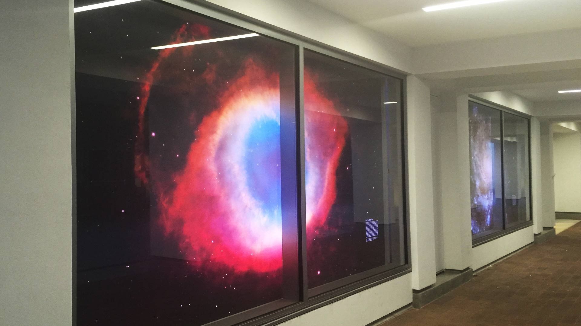 Large, illuminated prints of the Helix Nebula displayed in frames along a hallway wall.