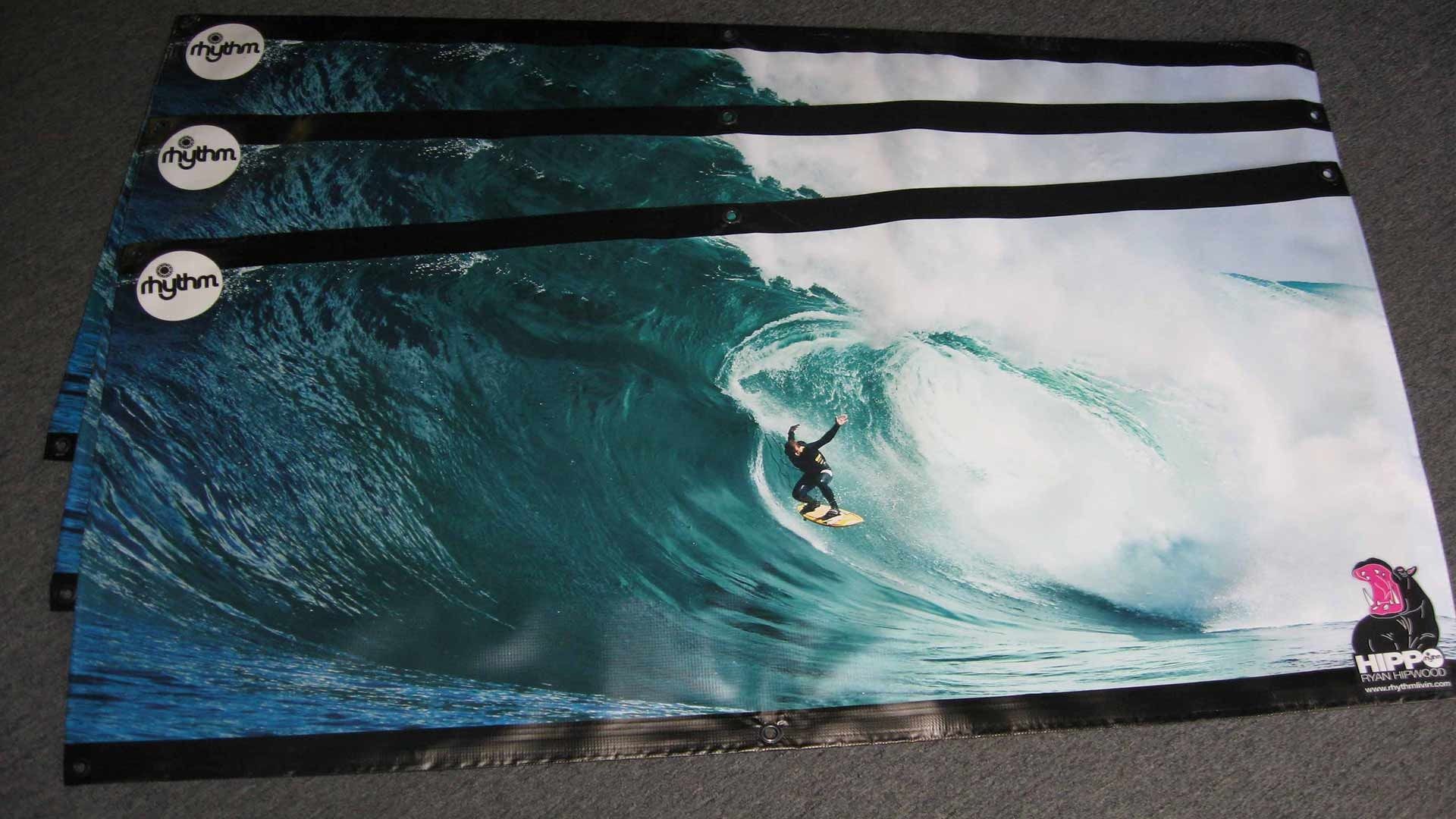 Three rectangular banners featuring a surfing scene with a large wave and a surfer, stacked on a grey surface.