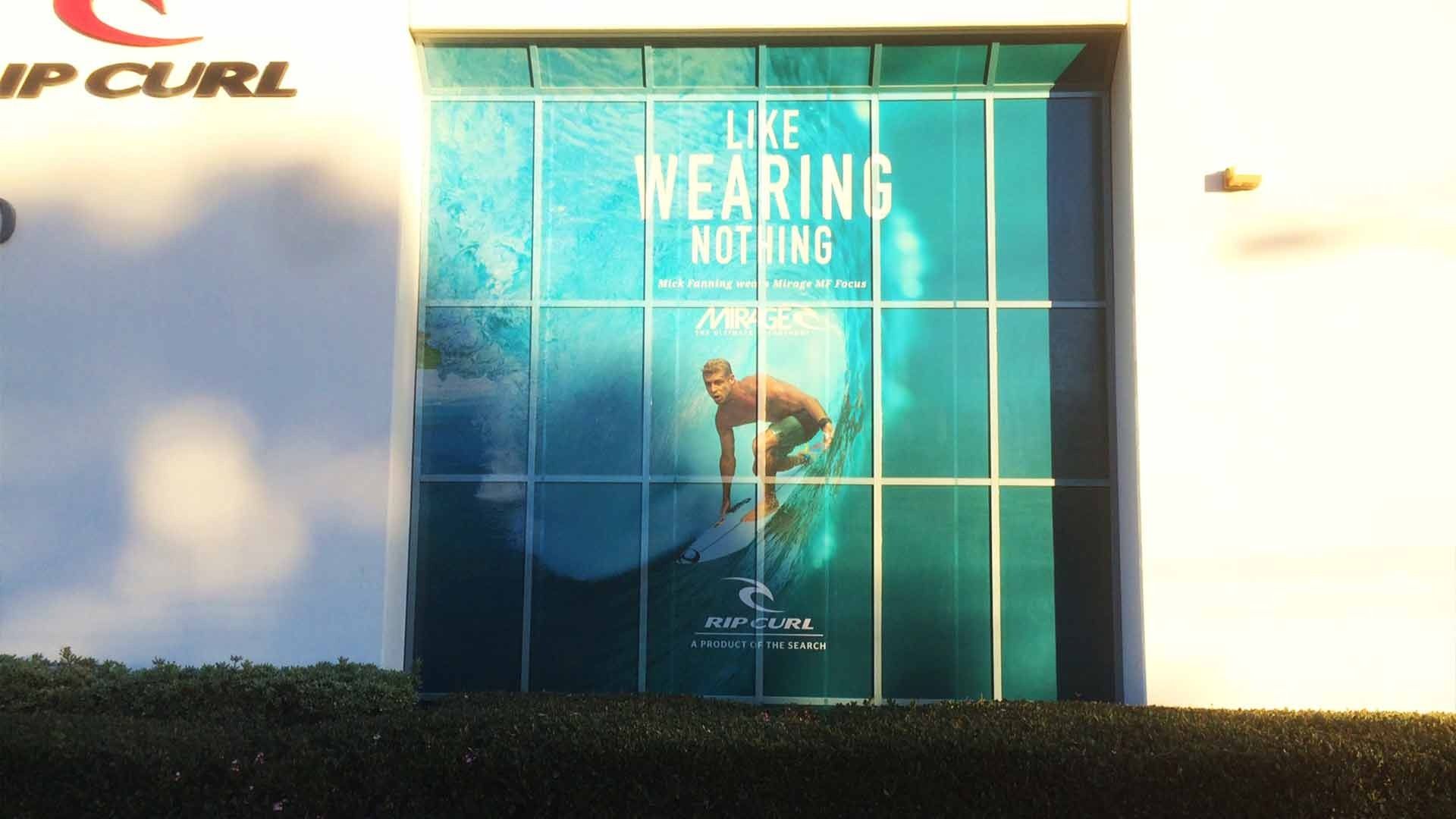 A Rip Curl storefront window features a surfer on a wave with the text, 