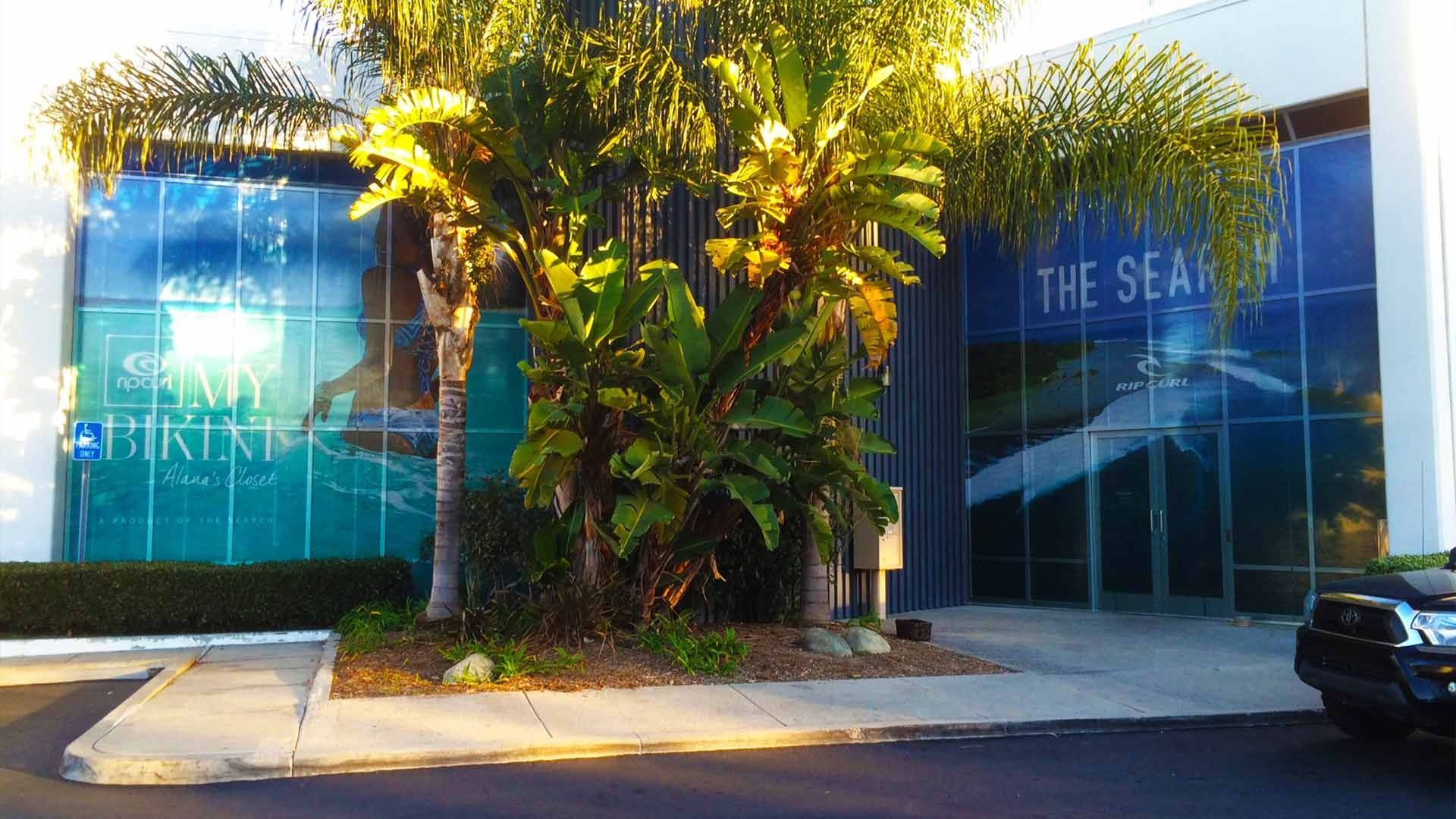 Exterior of a building featuring blue-tinted glass walls with text reading 