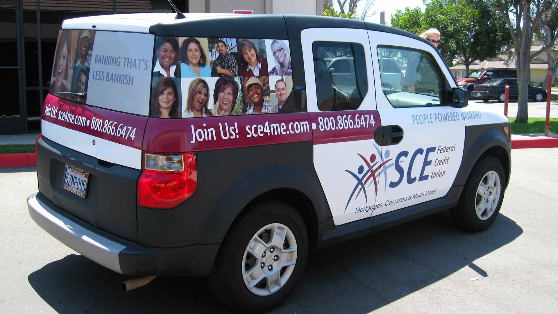 A white and dark burgundy branded vehicle with headshots, contact information, and an SCE logo parked outdoors.