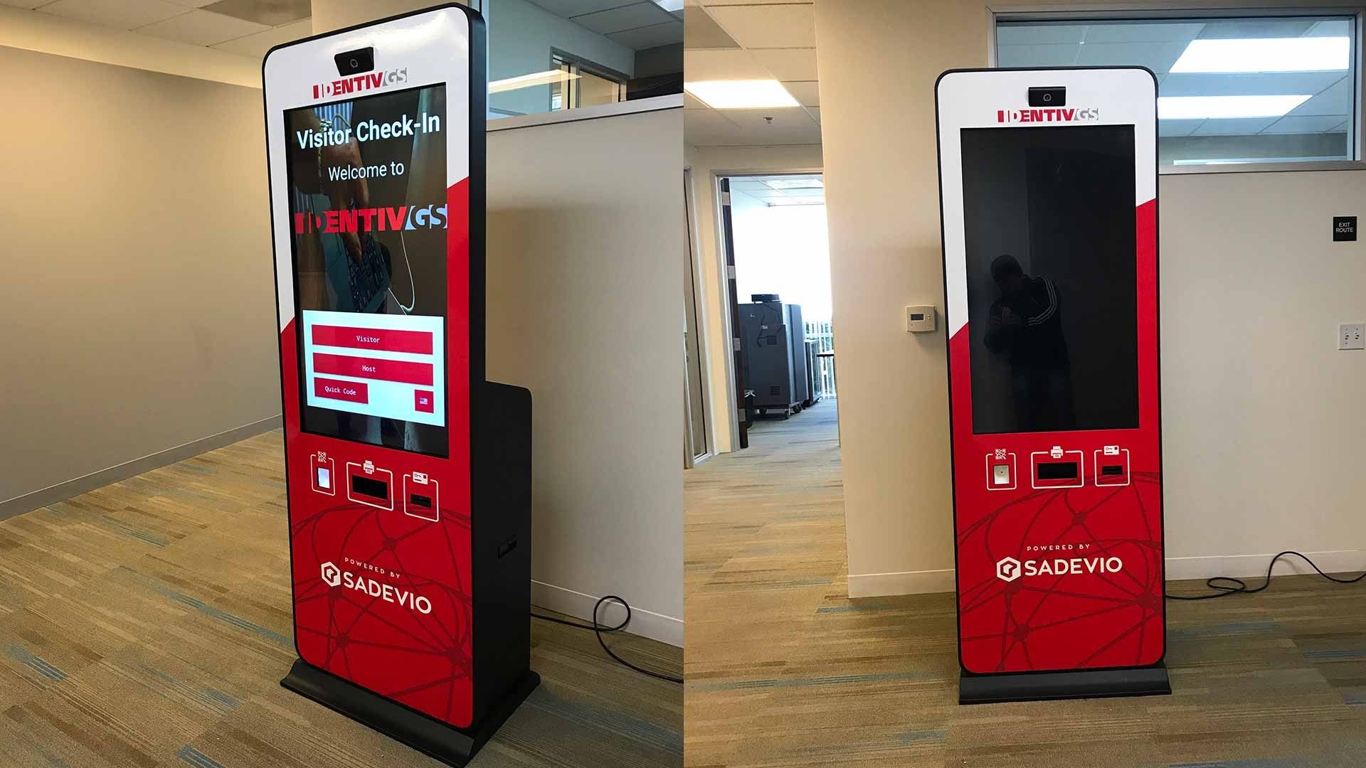 Two views of a red and white digital self-service check-in kiosk standing in a bright office space.
