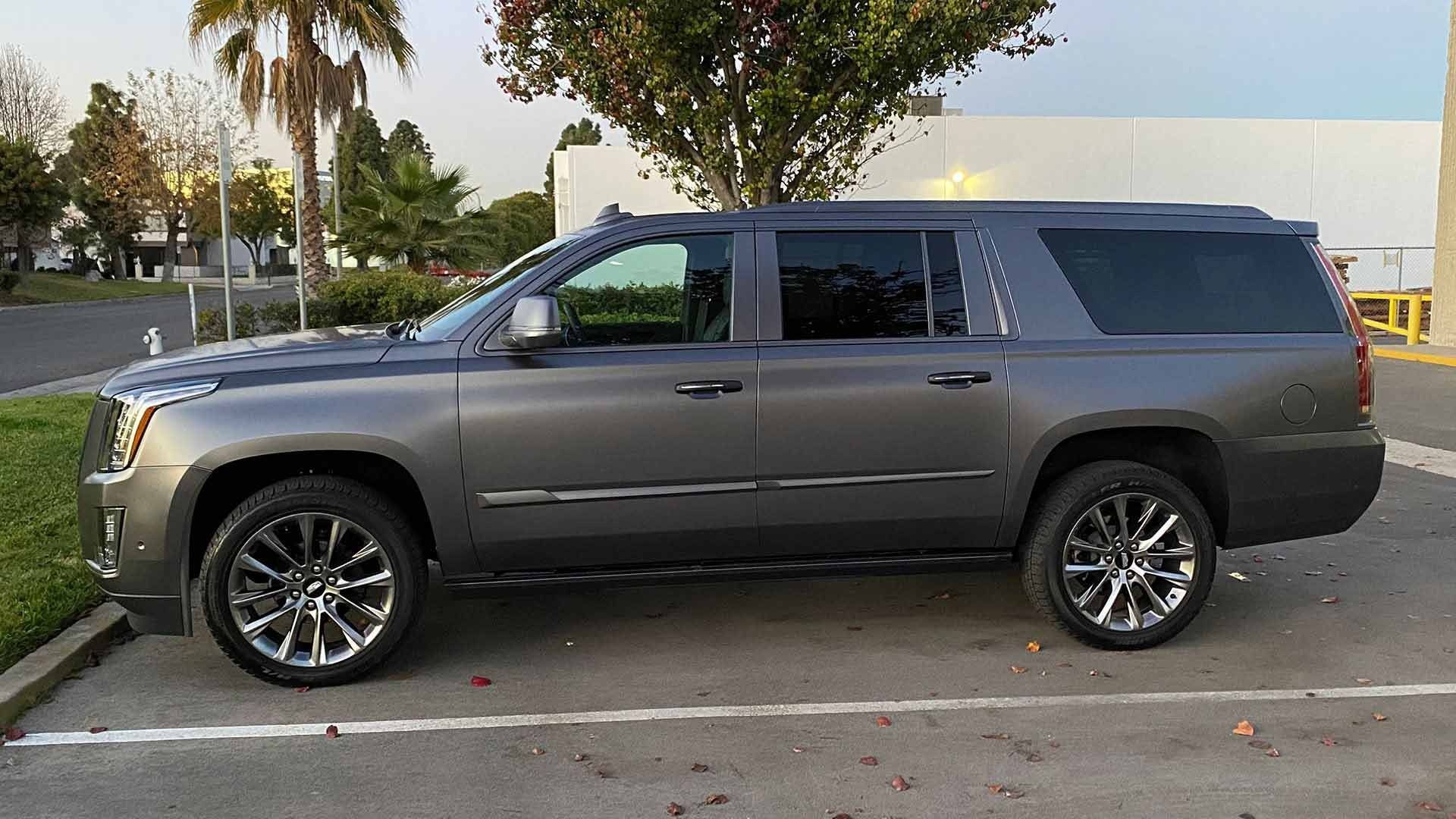 A dark gray Cadillac Escalade SUV parked in an outdoor lot on a sunny day.