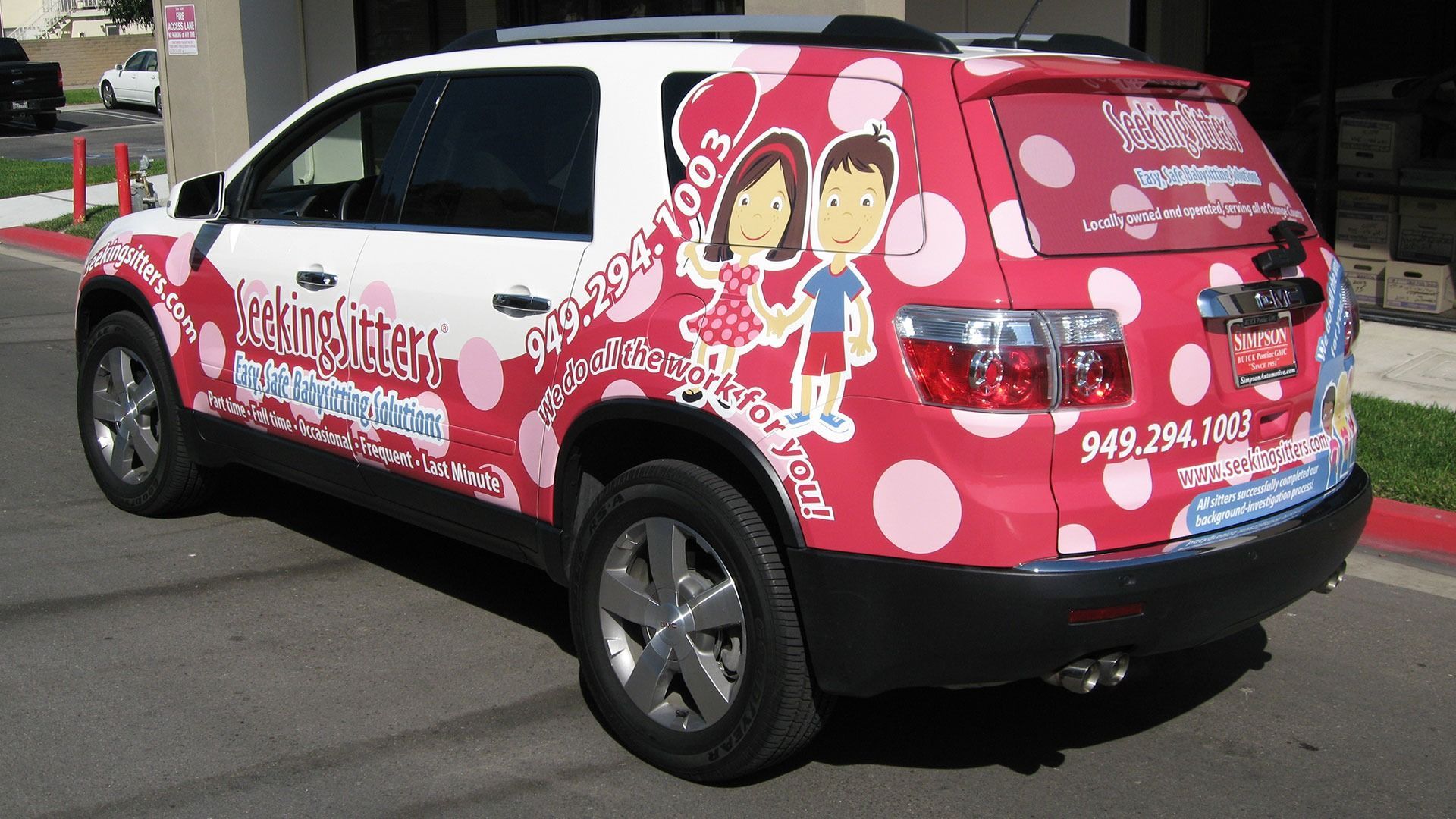 A white and pink polka-dotted SUV branded for a childcare service features a cartoon of two children and a phone number.