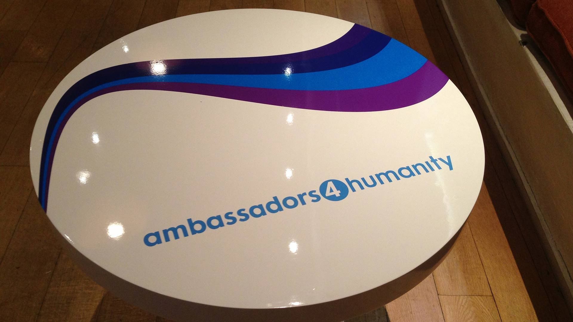 A round white table with a blue and purple wave graphic and the logo 