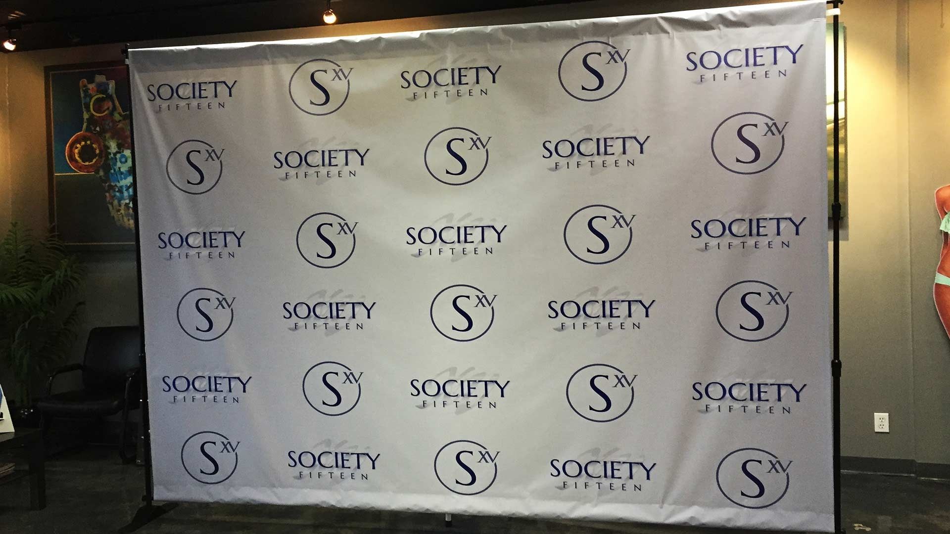 A white step and repeat backdrop featuring a repeating pattern of the black 