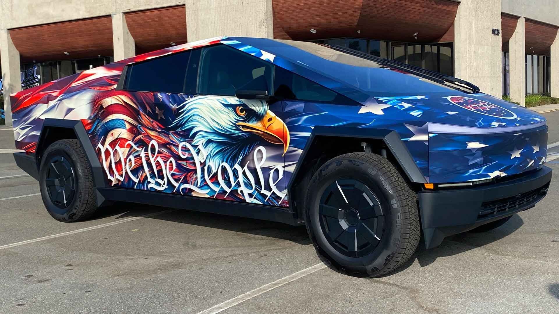 A Tesla Cybertruck parked in a lot, wrapped in a patriotic American flag design with a bald eagle and 