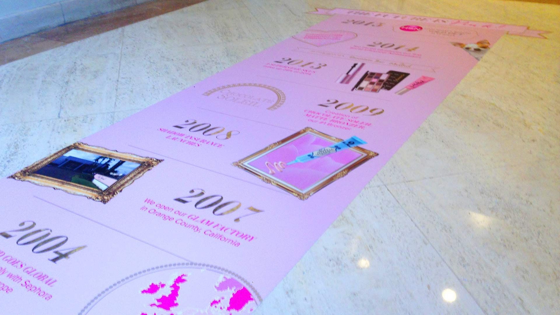 A pink timeline decal on a floor illustrates a company's historical milestones from 2004 to 2011 with text and icons.