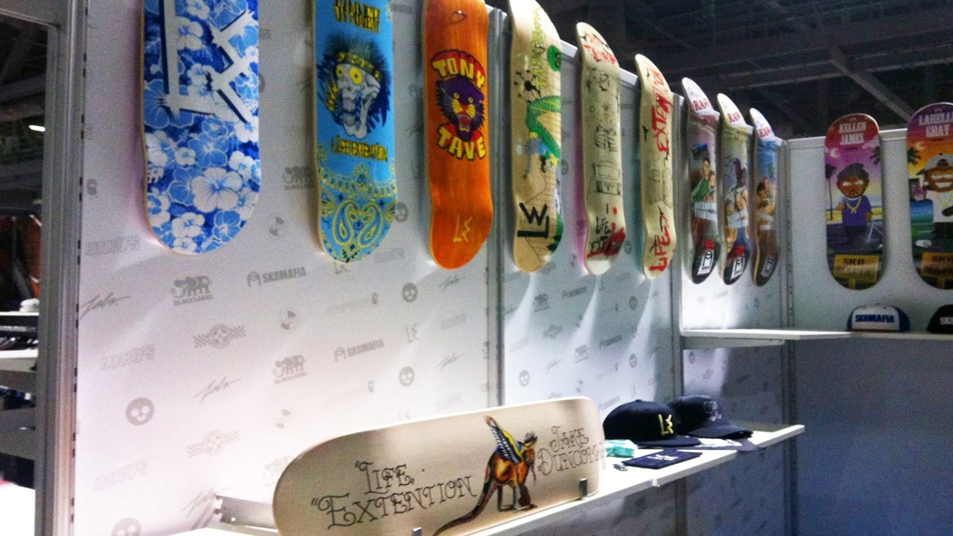 A display of colorful patterned skateboard decks hanging on a wall, with one deck resting on a shelf below.