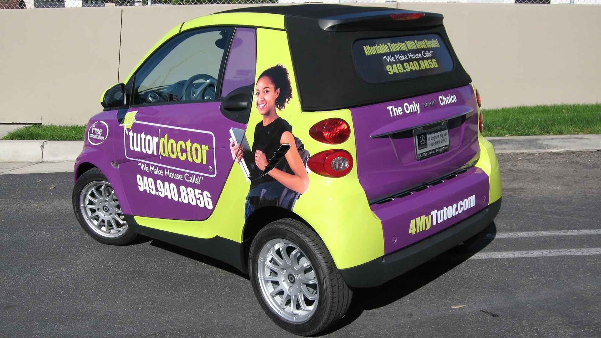 A purple and neon yellow Tutor Doctor smart car parked on an asphalt street.