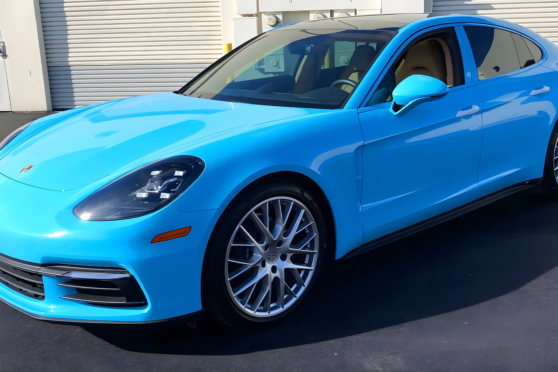 A bright blue Porsche Panamera sedan parked on an asphalt lot.