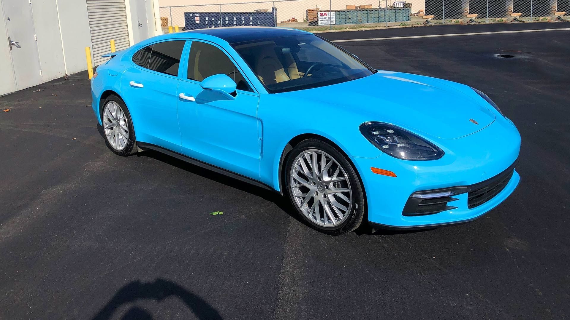 A bright blue Porsche Panamera parked on an asphalt lot.