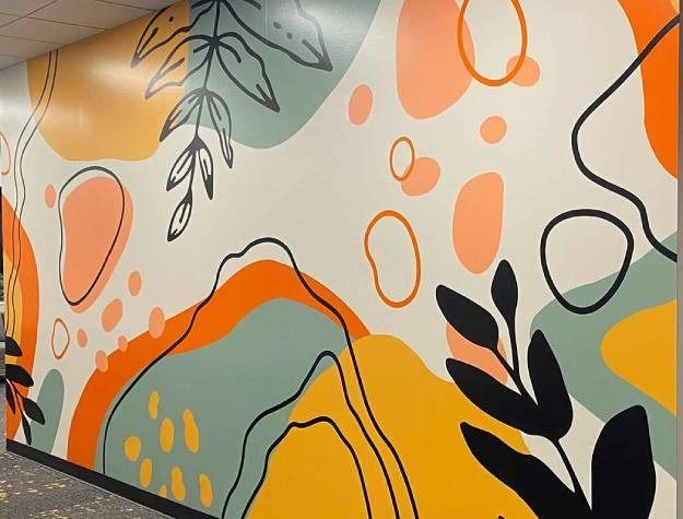 A wall mural featuring abstract organic shapes in yellow, orange, and sage green with black line-drawn botanical elements.