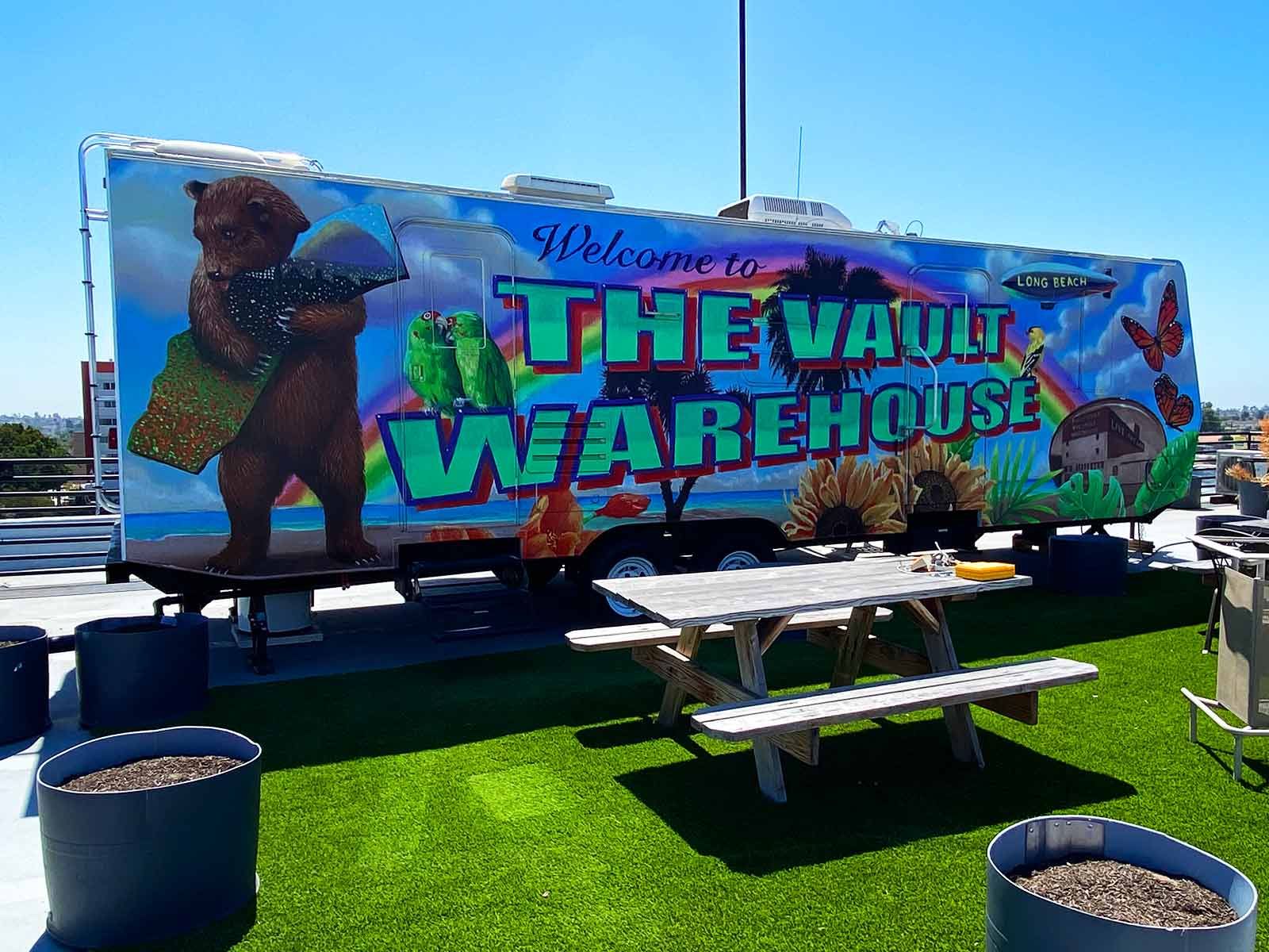 A large, colorful mural on a parked trailer reads