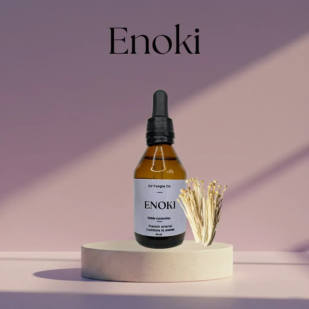 Botella de tintura de Enoki con hongos enoki, sobre un pedestal beige sobre un fondo rosa.