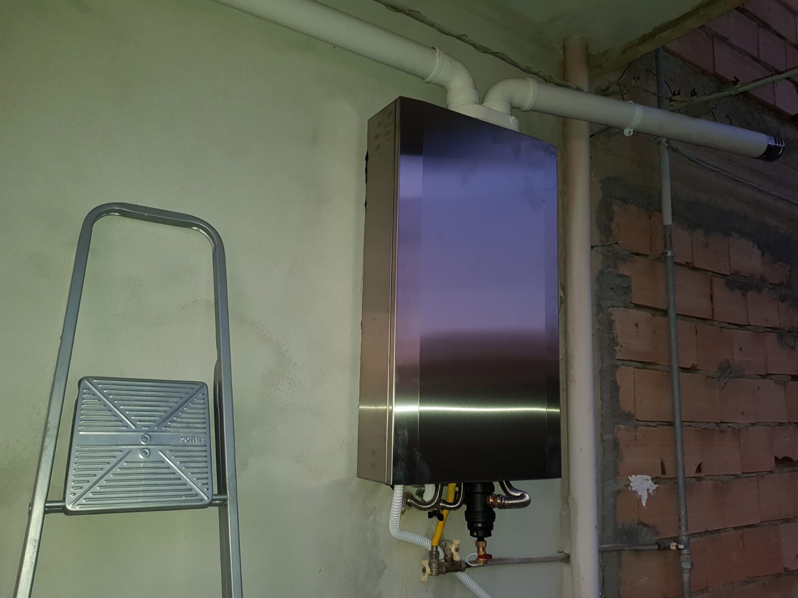 Una scala è appoggiata a un muro accanto a una scatola di acciaio inossidabile