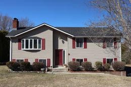 A large house with two garage doors and a driveway in front of it.