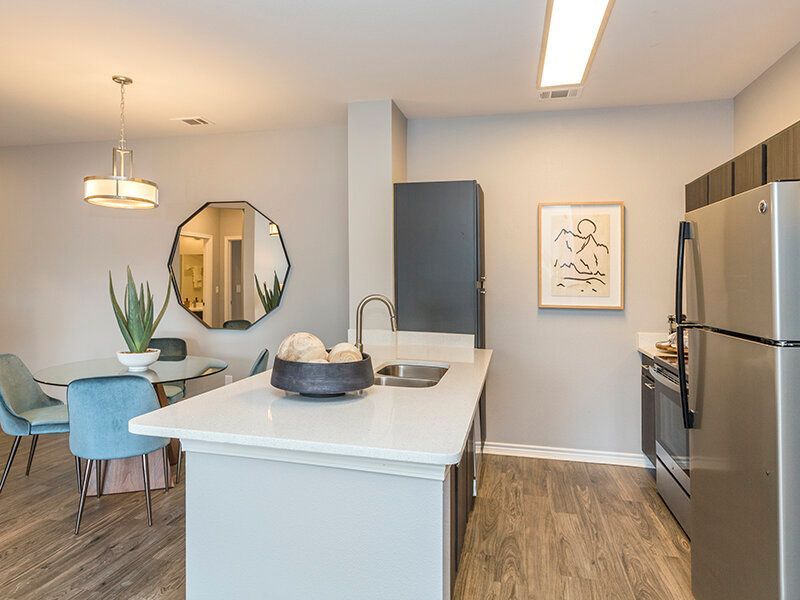 Modern kitchen with an island, sink, and stainless-steel refrigerator.
