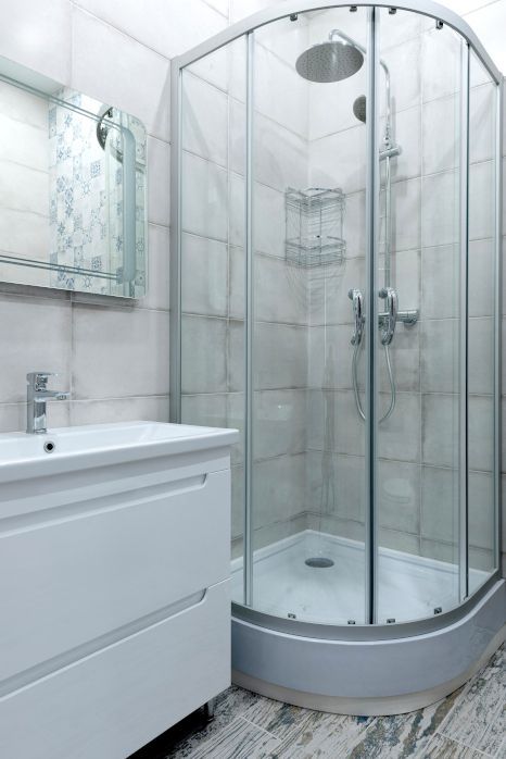 A bathroom with a shower stall , sink and mirror. Shower expertly sealed by Rose Tiling in Stoke-on-Trent.