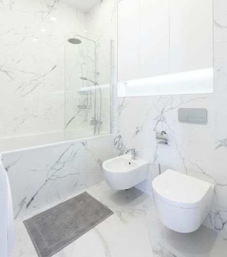 A marble tiled bathroom with a toilet , bidet, bathtub and shower in Stoke-on-Trent, UK.