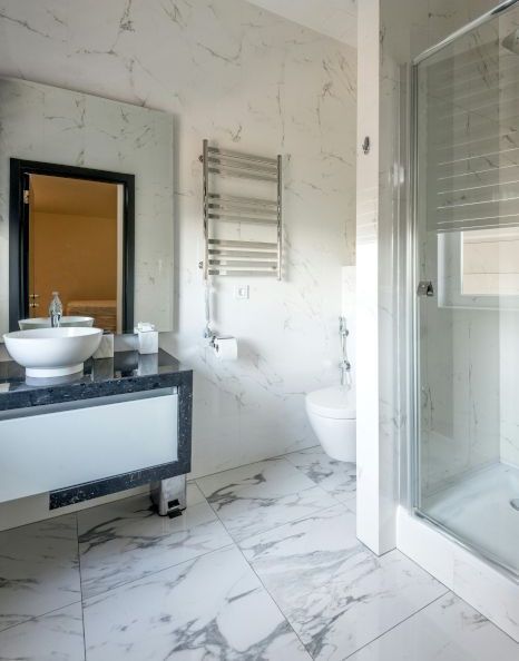 A bathroom with a toilet a sink and a mirror. Shower expertly sealed by Rose Tiling in Stoke-on-Trent.