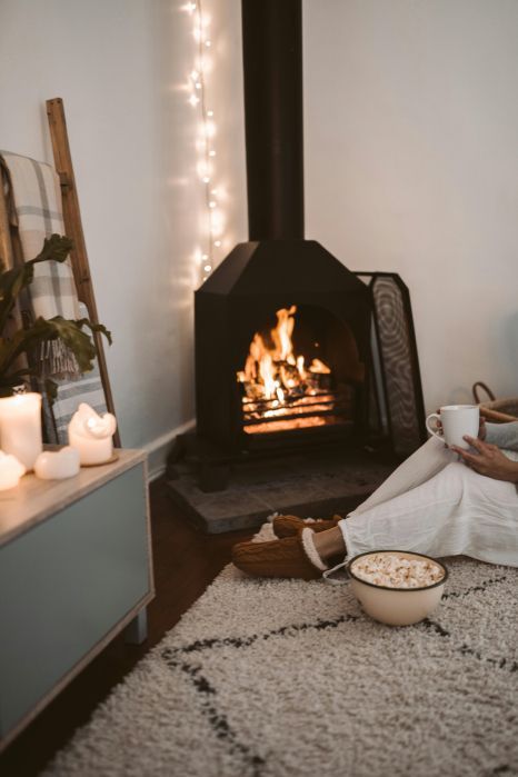 A person is sitting in front of a fireplace in a living room.