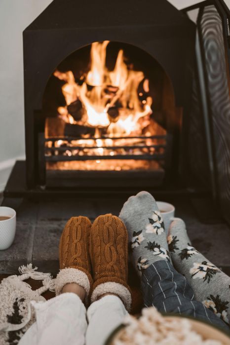 A couple of people are laying in front of a fireplace.