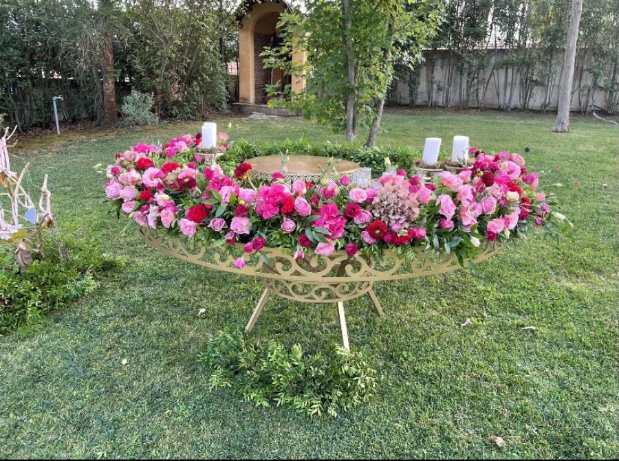 tavolo tondo con composizione di fiori rosa e fucsia