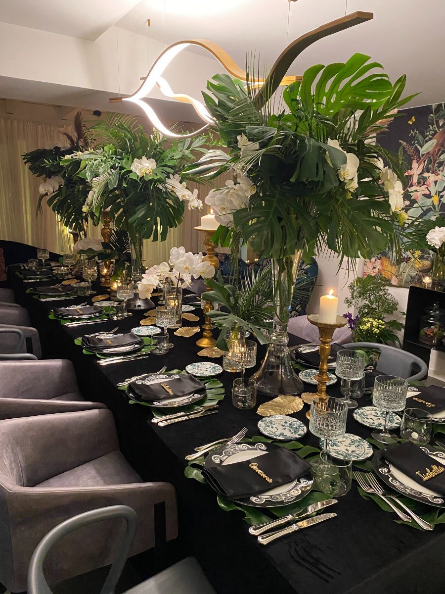 tavolo allestito con piante alte, orchidee e tovaglia nera