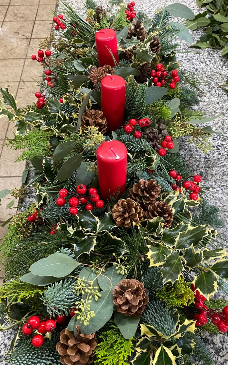 centrotavola natalizio con agrifogli e candele rosse