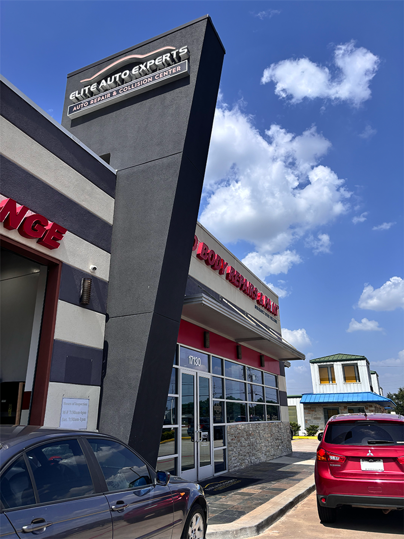 A red car is parked in front of a large building. | Elite Auto Experts