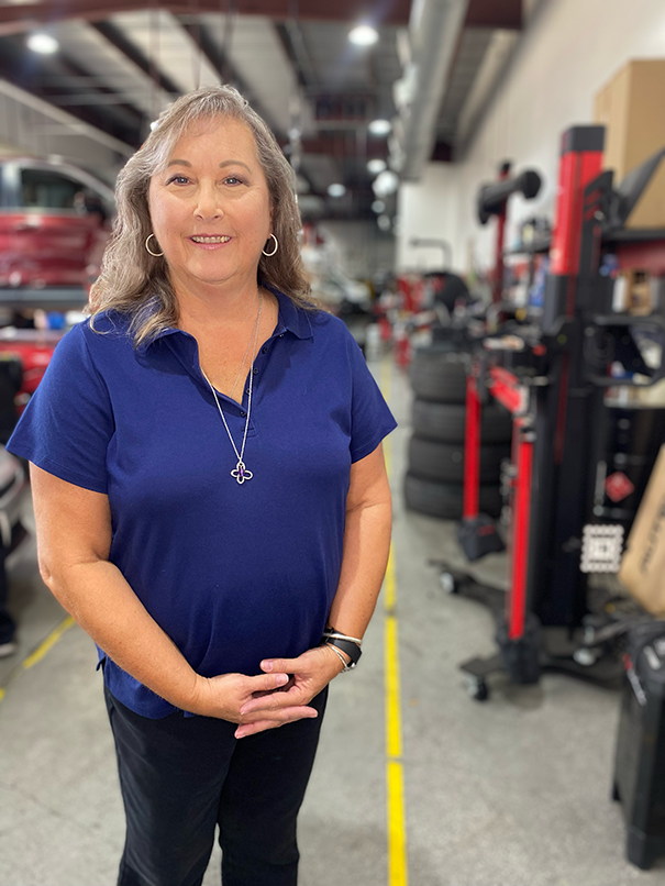 A woman in a blue shirt is standing in a garage. | Elite Auto Experts