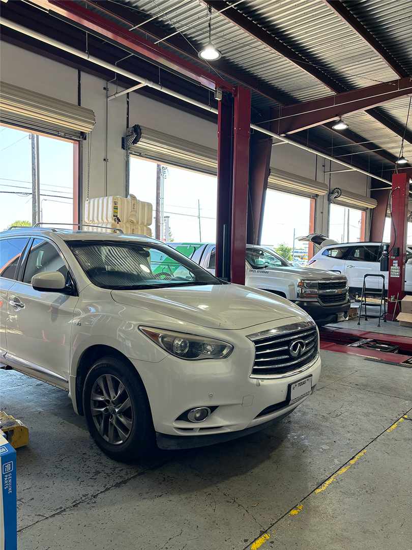 A white car is parked in a garage on a lift. | Elite Auto Experts