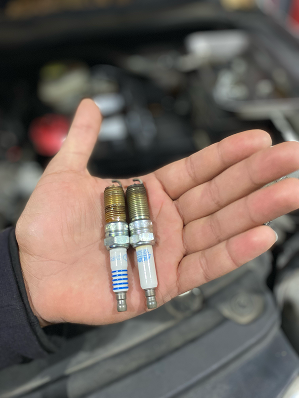 A person is holding two spark plugs in their hand | Elite Auto Experts