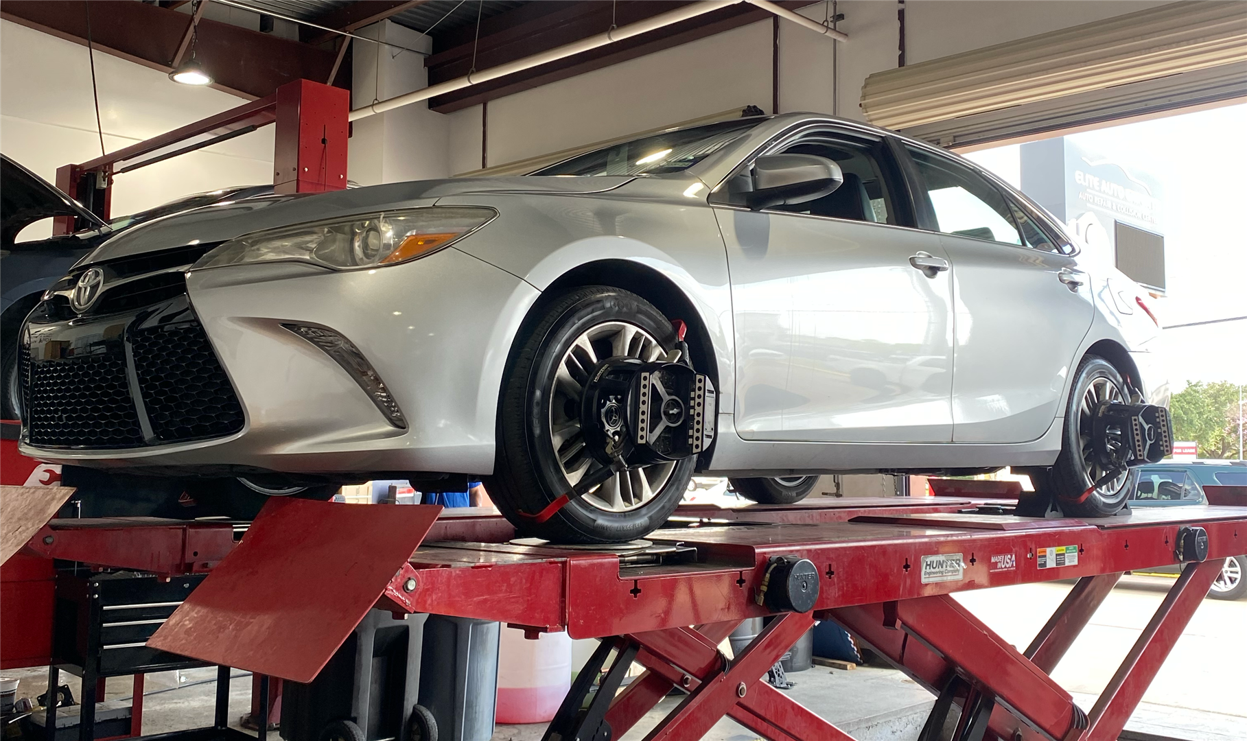 A silver car is sitting on top of a red lift in a garage. | Elite Auto Express