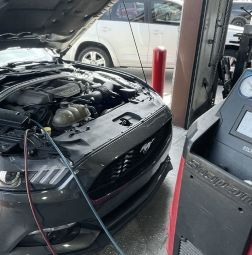 A car is being serviced in a garage with the hood up. | Elite Auto Experts
