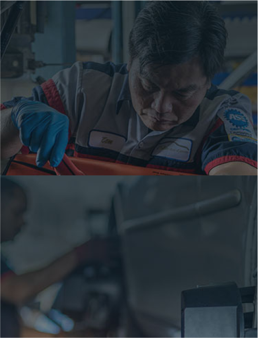 A man in a mechanic 's uniform is working on a car in a garage. | Elite Auto Experts