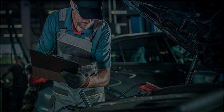 A mechanic is working on a car in a garage while looking at a clipboard. | Elite Auto Express