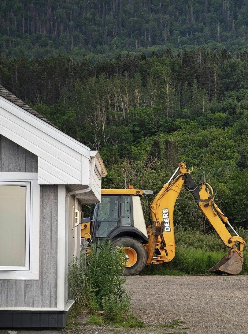 A yellow tractor is parked in front of a house.