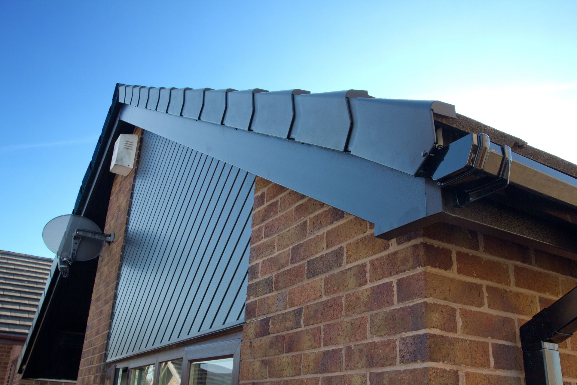 A brick building with a roof and gutter on it.
